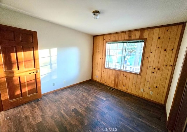 spare room with wood walls and dark hardwood / wood-style flooring