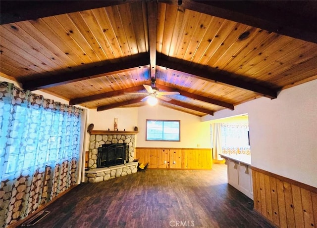 unfurnished living room with ceiling fan, a stone fireplace, lofted ceiling with beams, dark hardwood / wood-style floors, and wooden walls