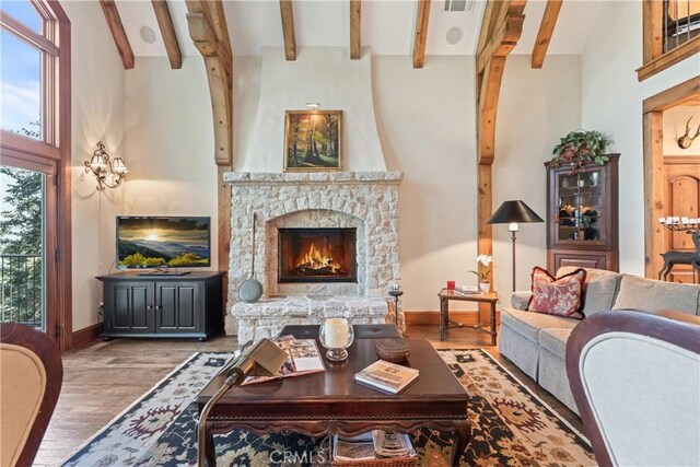 living room with high vaulted ceiling, wood-type flooring, beamed ceiling, and a fireplace