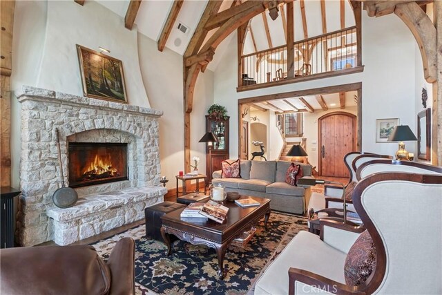 living room featuring high vaulted ceiling, beamed ceiling, and a stone fireplace