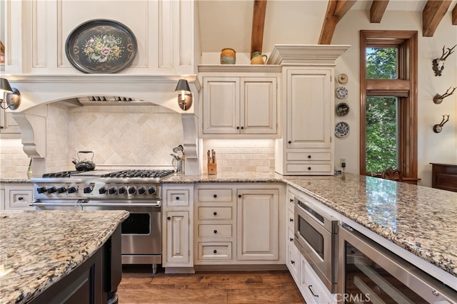 kitchen with beamed ceiling, dark wood-type flooring, light stone counters, and stainless steel appliances