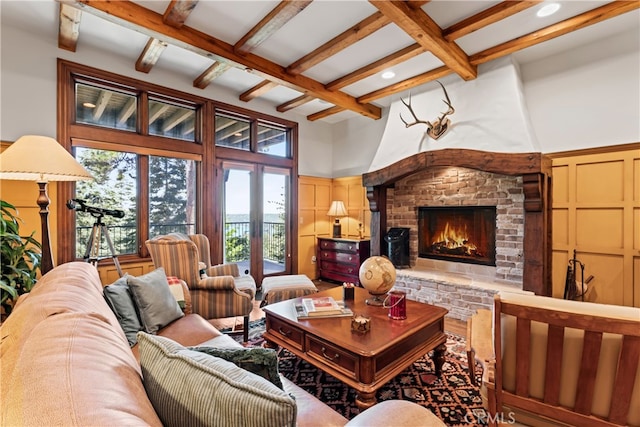 living room featuring beam ceiling, a high ceiling, and a brick fireplace