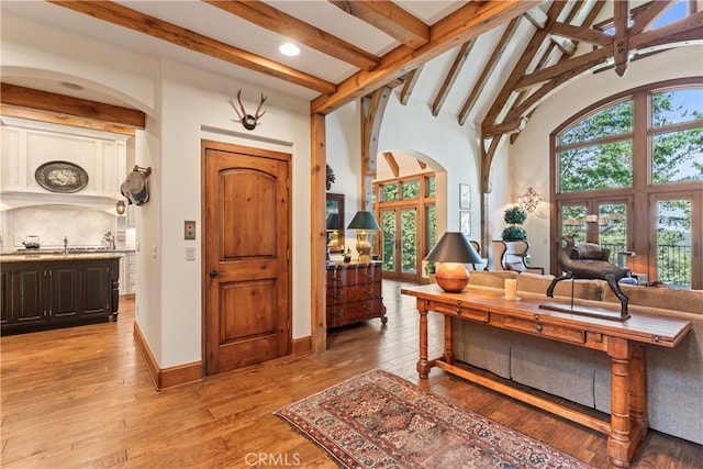 interior space featuring beam ceiling, light hardwood / wood-style flooring, and high vaulted ceiling