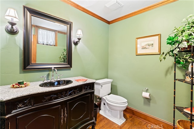 bathroom with vanity, ornamental molding, wood-type flooring, and toilet