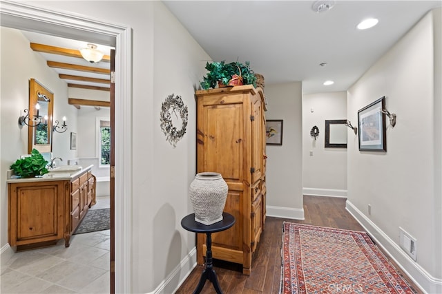 hallway featuring beam ceiling, sink, and hardwood / wood-style floors