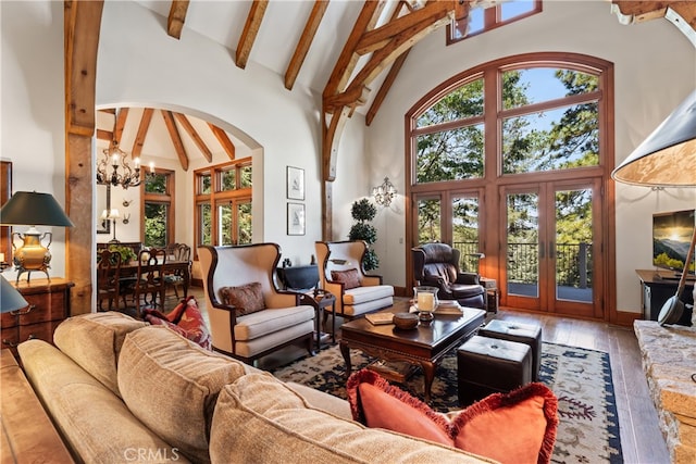 living room with beam ceiling, hardwood / wood-style flooring, high vaulted ceiling, a chandelier, and french doors