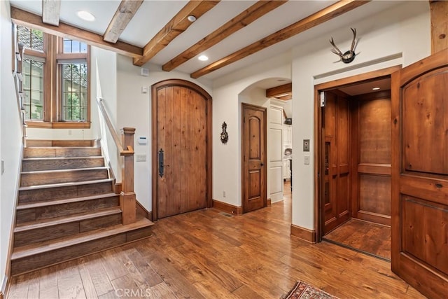 28964 Quail Run Ct, Lake Arrowhead, CA 92352 - foyer with arched walkways, beam ceiling, hardwood / wood-style floors, baseboards, and stairs