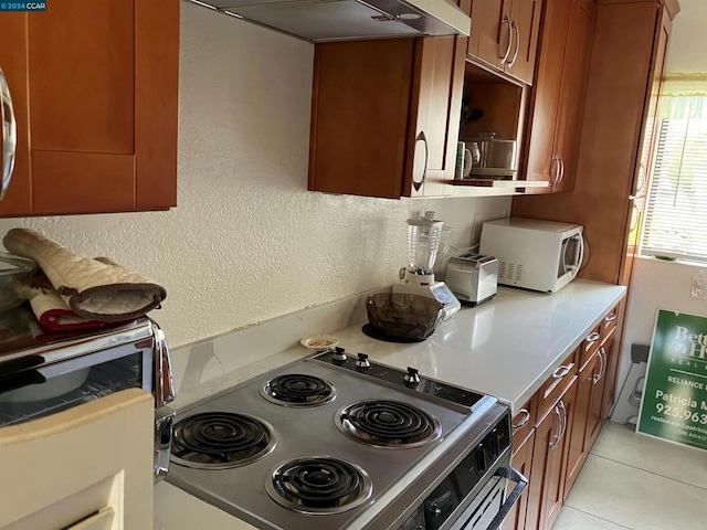 kitchen featuring light tile patterned floors, stainless steel electric range oven, and range hood