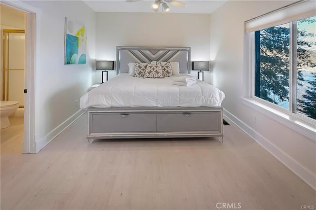 bedroom featuring multiple windows, ceiling fan, light hardwood / wood-style flooring, and ensuite bath