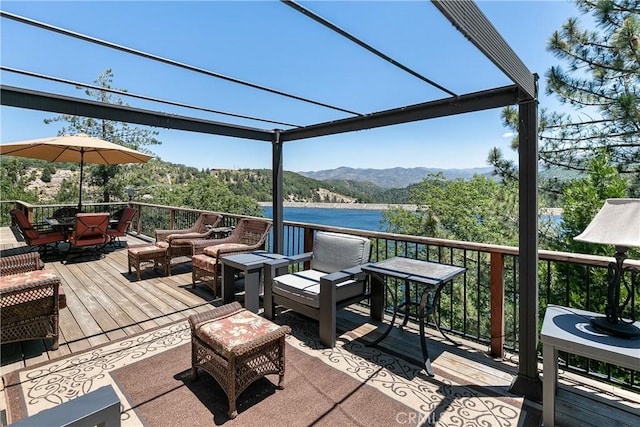 wooden terrace with a pergola, a water and mountain view, and an outdoor hangout area