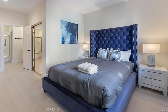 bedroom featuring ensuite bathroom and light hardwood / wood-style flooring