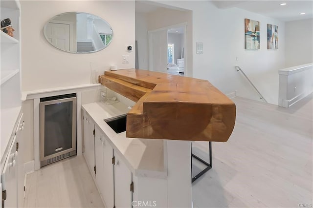 bar with white cabinets, light hardwood / wood-style floors, and wine cooler