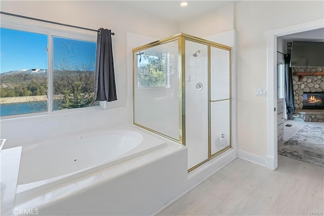 bathroom featuring separate shower and tub, a fireplace, and hardwood / wood-style floors