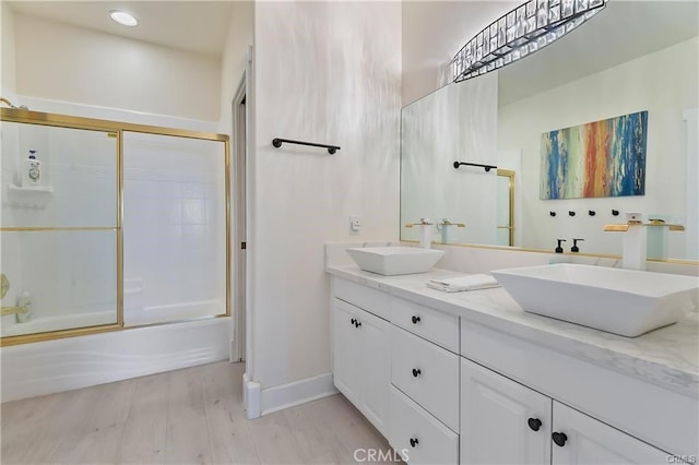 bathroom featuring hardwood / wood-style floors, vanity, and combined bath / shower with glass door