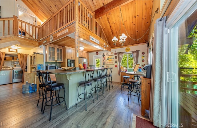 kitchen featuring hardwood / wood-style floors, decorative light fixtures, high vaulted ceiling, and washer and dryer