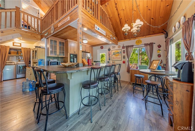 kitchen featuring hardwood / wood-style flooring, stainless steel appliances, wooden ceiling, decorative light fixtures, and washer and dryer