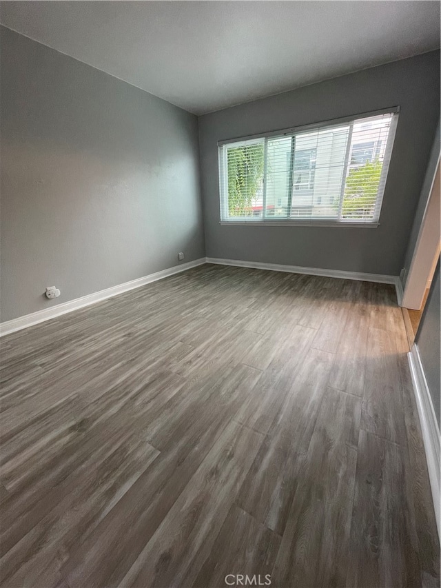 empty room with dark hardwood / wood-style floors and a healthy amount of sunlight