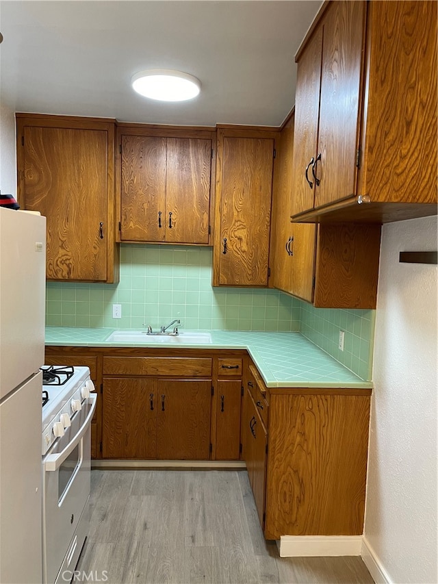 kitchen featuring tasteful backsplash, sink, white appliances, and light wood-type flooring