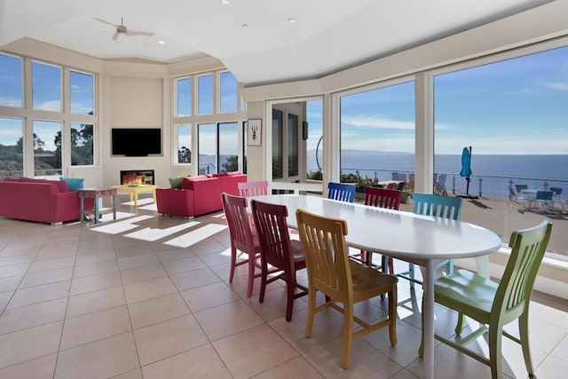 tiled dining area featuring a water view, ceiling fan, and plenty of natural light