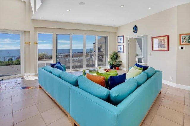 living room featuring light tile patterned floors, a healthy amount of sunlight, and a water view