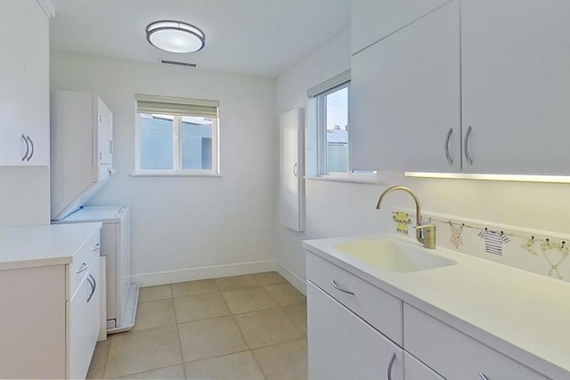 clothes washing area featuring light tile patterned flooring, cabinets, and sink