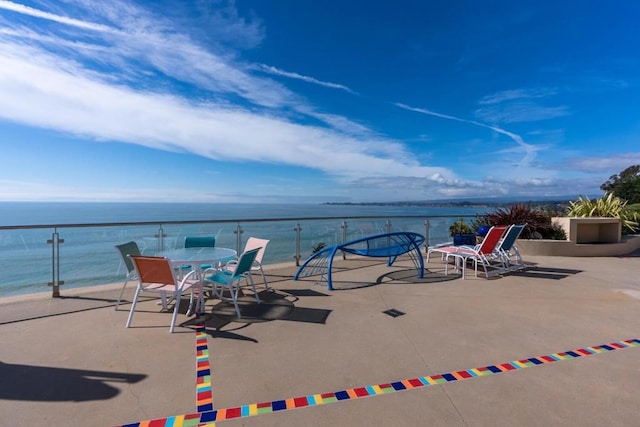 view of patio / terrace with a balcony, a water view, and a beach view