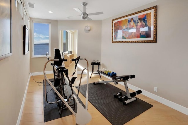 workout area with a water view, ceiling fan, and light hardwood / wood-style floors