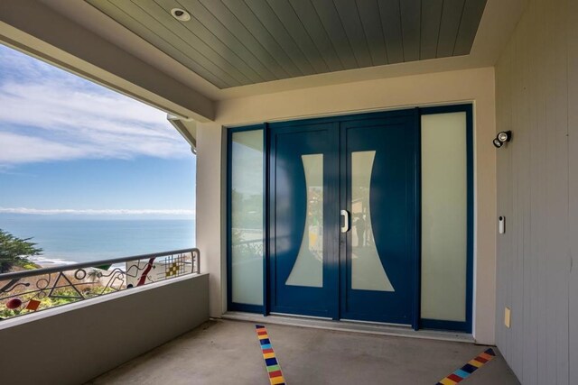 doorway to property with a balcony and a water view