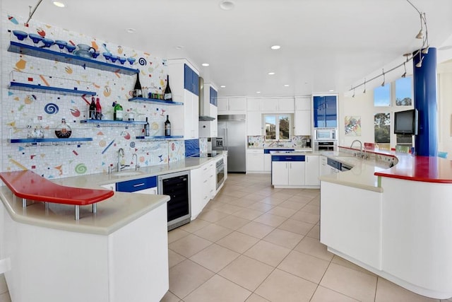 kitchen featuring white cabinets, sink, beverage cooler, and kitchen peninsula