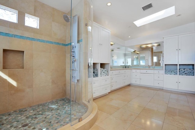 bathroom featuring a skylight, tile walls, a tile shower, vanity, and tile patterned flooring