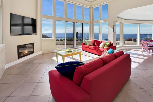 tiled living room featuring a water view and a towering ceiling