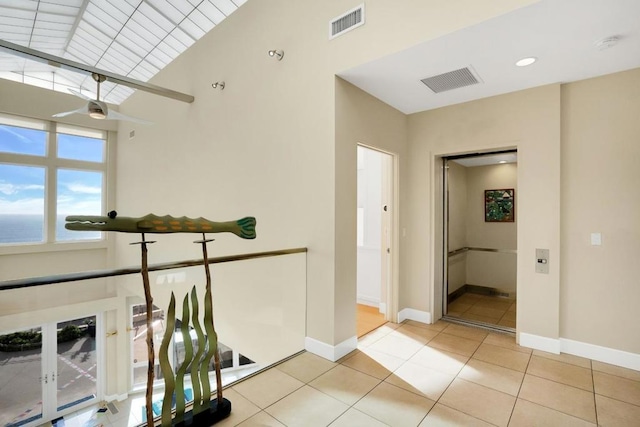 hall featuring light tile patterned floors and a water view