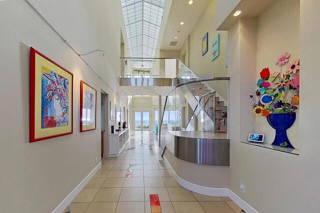 hallway with light tile patterned floors and a towering ceiling