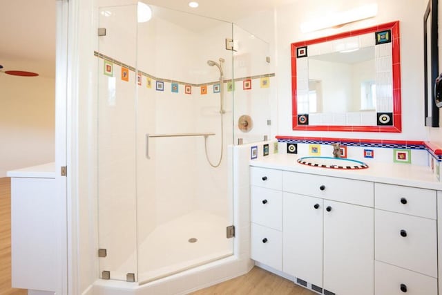 bathroom with vanity, hardwood / wood-style floors, decorative backsplash, and a shower with shower door