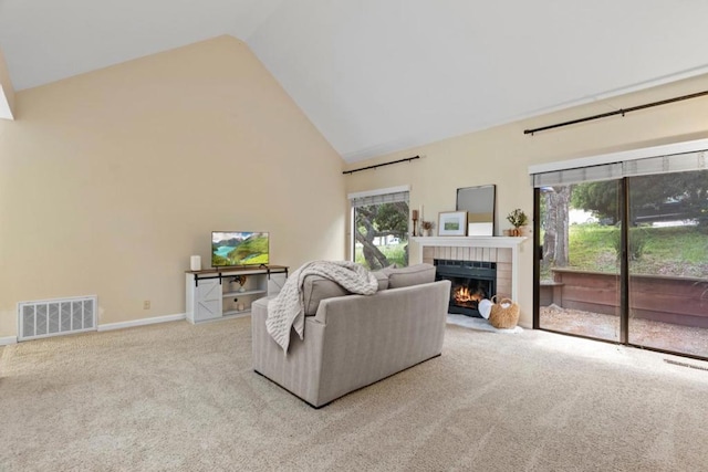 carpeted living room featuring a brick fireplace and high vaulted ceiling