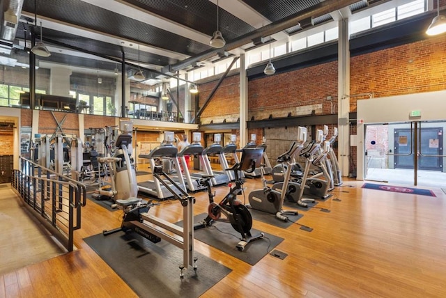 workout area featuring hardwood / wood-style floors, a towering ceiling, and ceiling fan