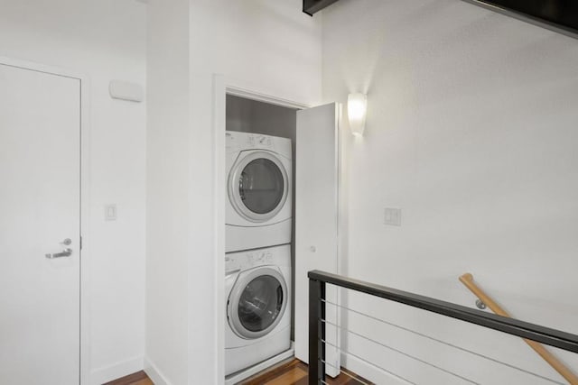 clothes washing area featuring wood-type flooring and stacked washer and clothes dryer