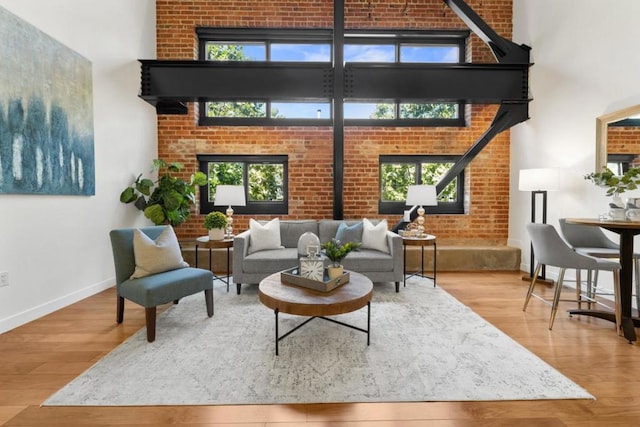 living room with a wealth of natural light, brick wall, and hardwood / wood-style flooring