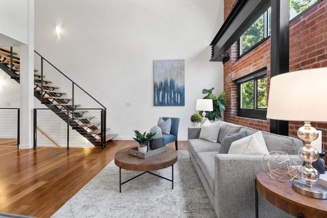 living room featuring brick wall, hardwood / wood-style floors, and a high ceiling