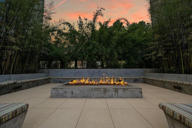 pool at dusk with a fire pit and a patio area