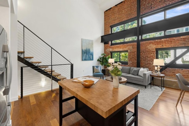 dining area featuring a towering ceiling, a healthy amount of sunlight, and hardwood / wood-style flooring