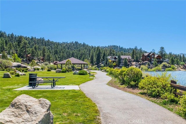 view of property's community with a water view, a gazebo, and a lawn