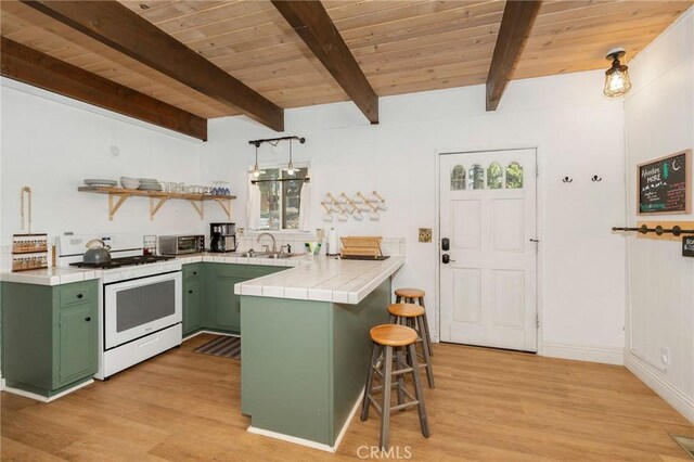 kitchen featuring green cabinets, a kitchen breakfast bar, light hardwood / wood-style floors, white range oven, and tile counters