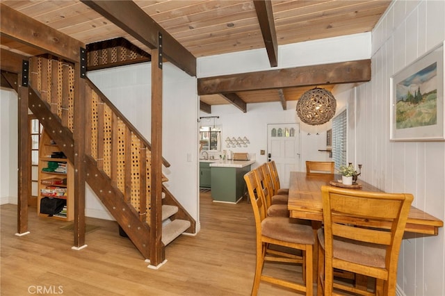 dining room featuring wood walls, beamed ceiling, light hardwood / wood-style floors, and wooden ceiling