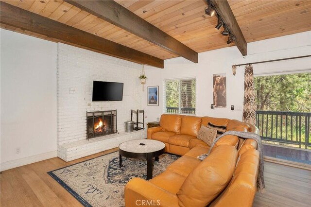 living room featuring beam ceiling, light hardwood / wood-style flooring, wood ceiling, and a fireplace