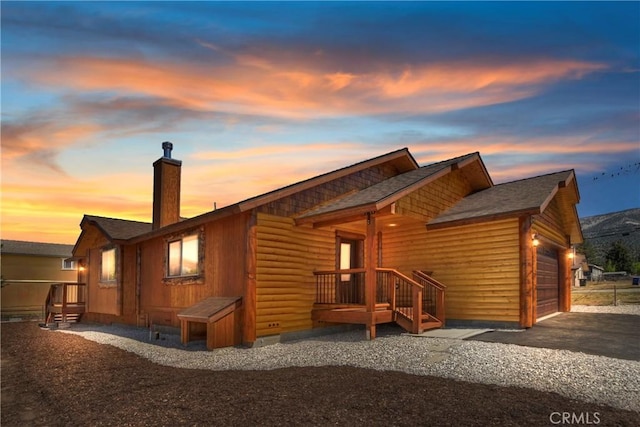 back house at dusk featuring a garage