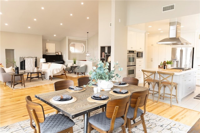 dining room featuring light hardwood / wood-style floors and a towering ceiling