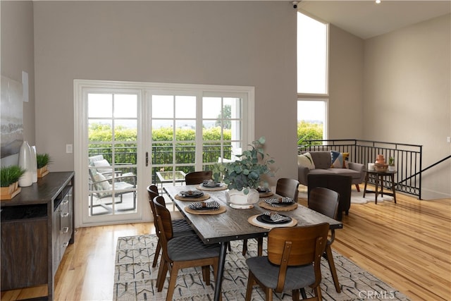 dining space with light hardwood / wood-style flooring and a high ceiling