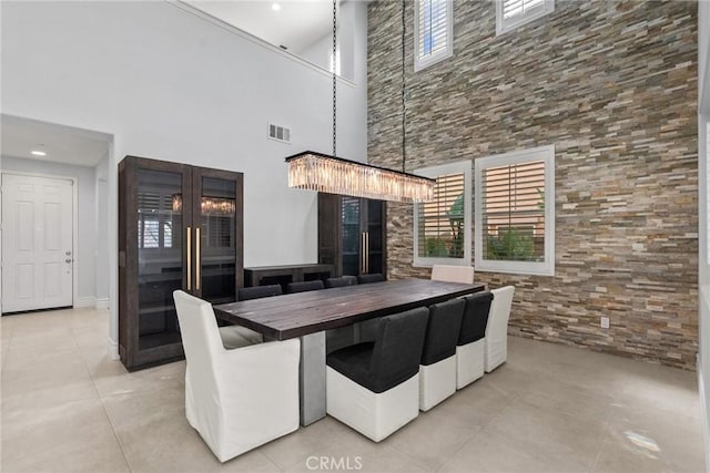 unfurnished dining area featuring a towering ceiling, light tile patterned floors, and an inviting chandelier