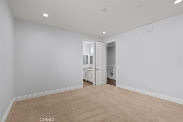 unfurnished bedroom with connected bathroom, light colored carpet, and sink